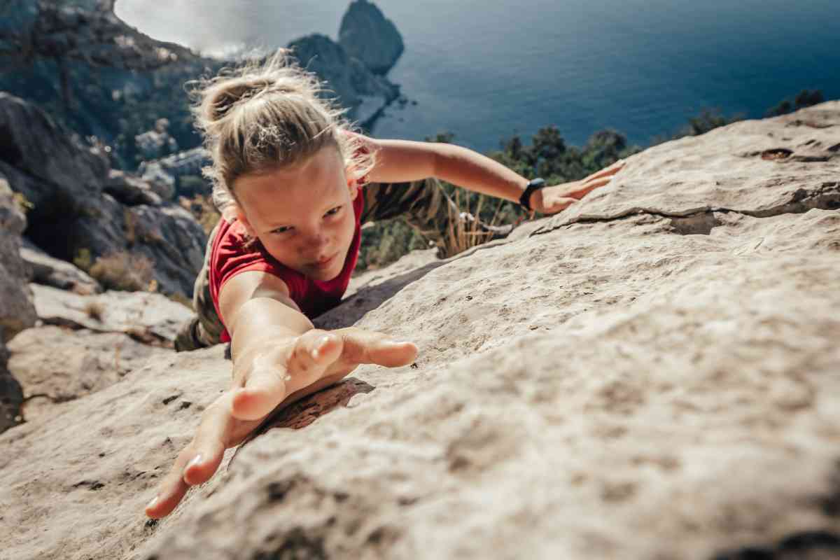 giovane donna scala una parete rocciosa